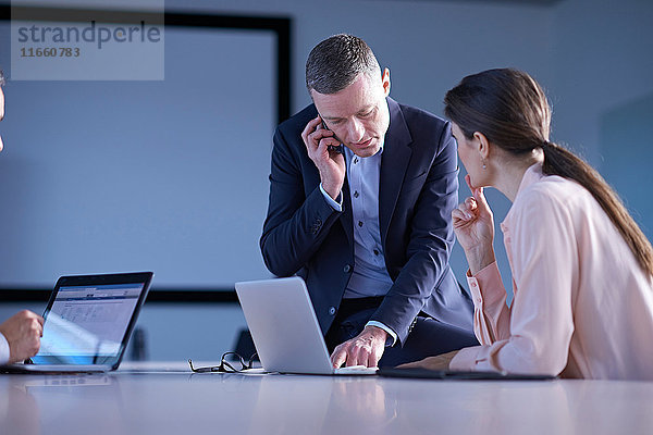 Geschäftsteam telefoniert mit Smartphone und Laptop auf dem Bürotisch