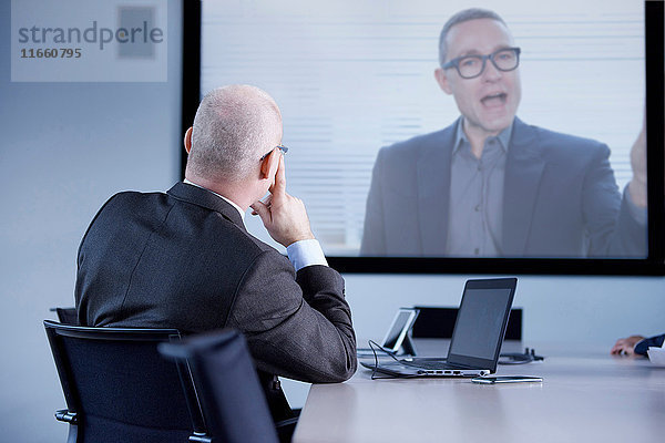 Geschäftsmann beobachtet Büro-Telefonkonferenz