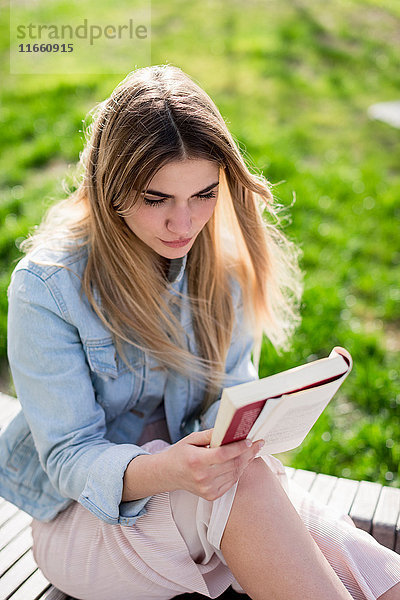 Junge Frau im Freien sitzend  Lesebuch