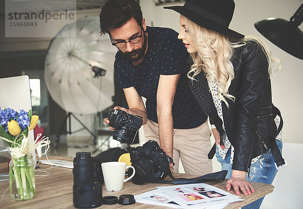 Fotograf und Stylist  der Fotografien auf einer Fotostudiokamera begutachtet