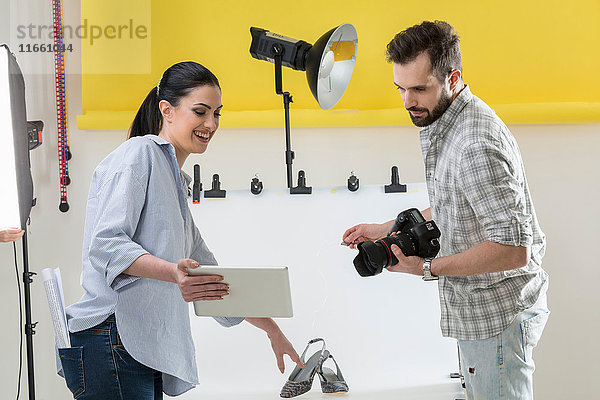 Stylist und Fotograf beim Betrachten eines digitalen Tabletts im Fotostudio