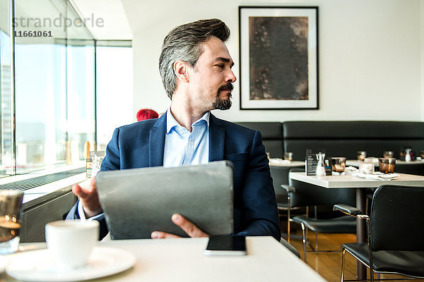 Geschäftsmann mit digitalem Tablett am Restaurantfenster  London  UK