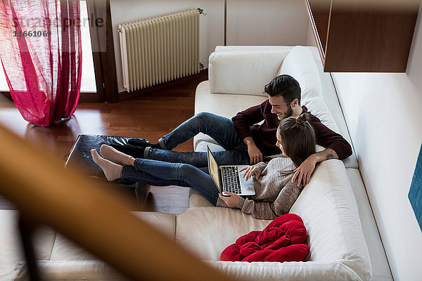 Junges Paar entspannt sich auf dem Sofa  schaut auf den Laptop  erhöhter Blick