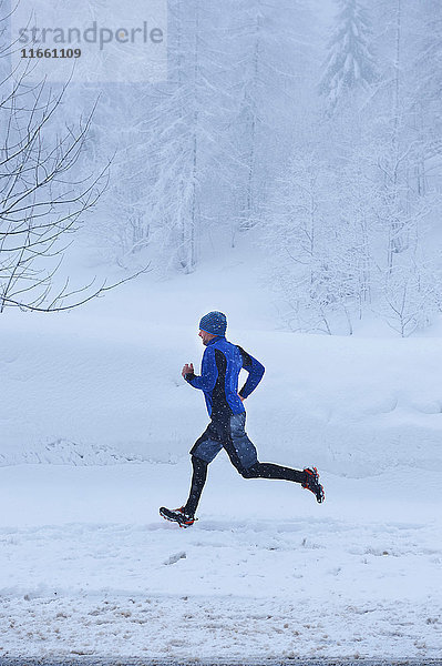 Männlicher Läufer läuft bei Schneefall  Gstaad  Schweiz