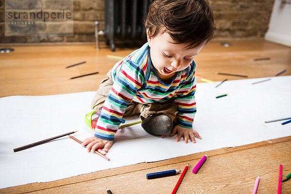 Männliches Kleinkind sitzt auf dem Boden Zeichnung auf langem Papier