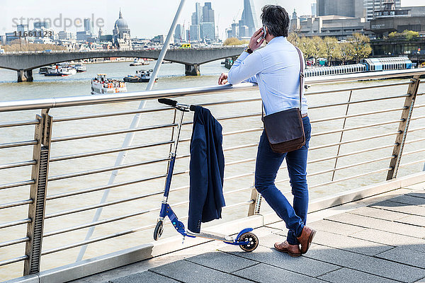 Geschäftsmann neben Roller  Hungerford Bridge  London  UK