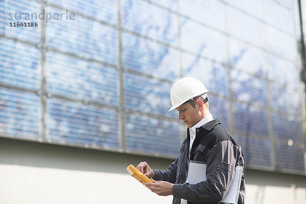 Männlicher Ingenieur benutzt Multimeter auf Solarzellenplatten