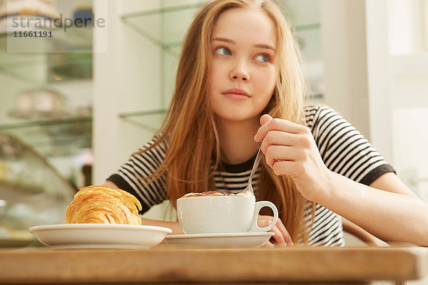 Mädchen im Café  das Kaffee umrührt