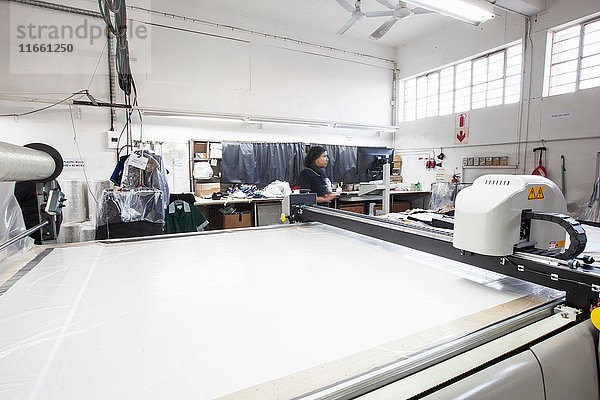 Musterschneidemaschine und Fabrikarbeiter in Bekleidungsfabrik