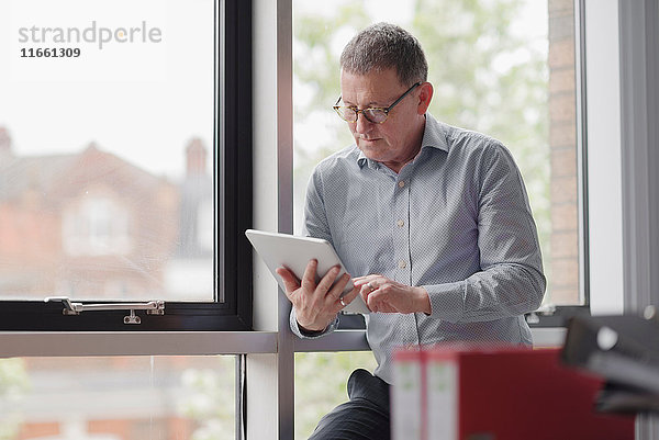 Mann benutzt digitales Tablett durch Bürofenster