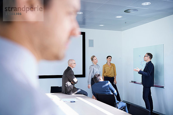 Geschäftsmann macht Whiteboard-Präsentation in Konferenzraum-Sitzung
