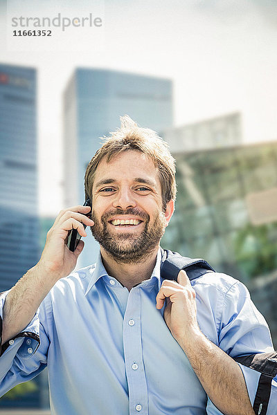 Porträt eines glücklichen Geschäftsmannes beim Smartphone-Anruf in der Stadt