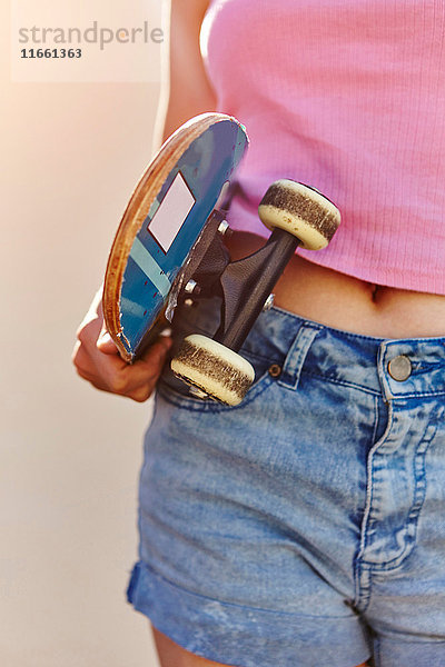 Teenagerin  im Freien  Skateboard haltend  Mittelteil