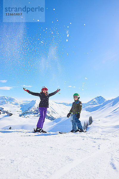 Porträt einer Ski fahrenden Teenagerin und ihres Bruders beim Pulverschneewerfen in den Schweizer Alpen  Gstaad  Schweiz