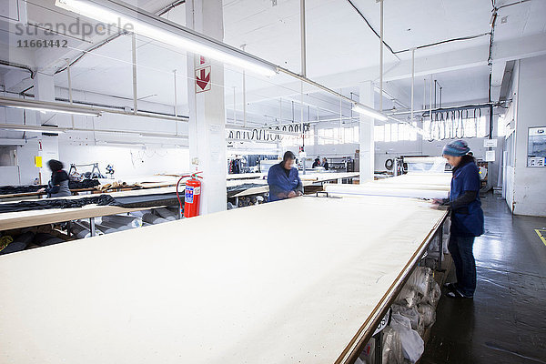 Männliche und weibliche Fabrikarbeiter markieren Textilien in Bekleidungsfabrik