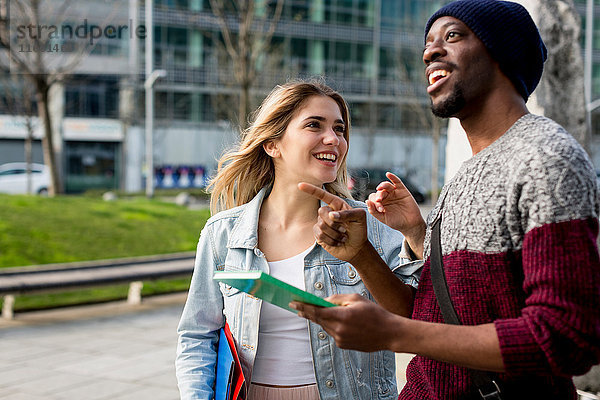Junges Paar  das im Freien spazieren geht  Notizbücher hält  lächelt
