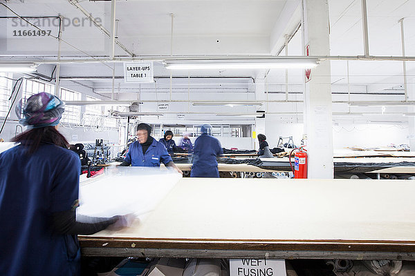 Fabrikarbeiterinnen rollen Textilien in Bekleidungsfabrik ab