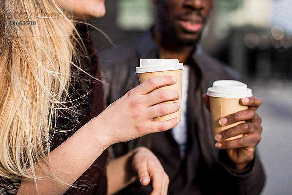 Ausschnitt eines jungen Paares mit Kaffee zum Mitnehmen in der Stadt