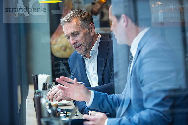 Zwei Geschäftsleute diskutieren im Restaurant am Fensterplatz