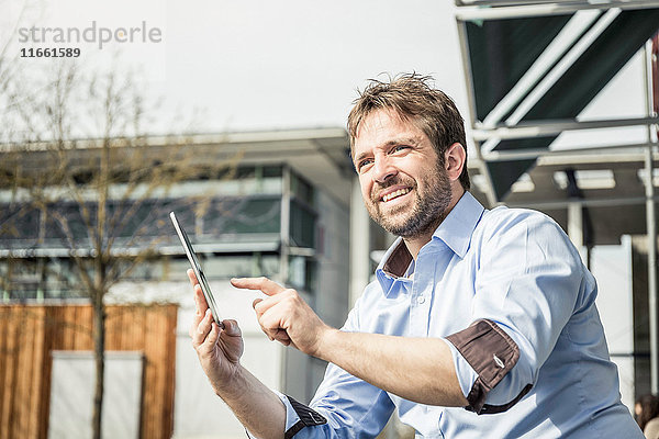 Geschäftsmann benutzt digitalen Tablet-Touchscreen vor dem Bürogebäude