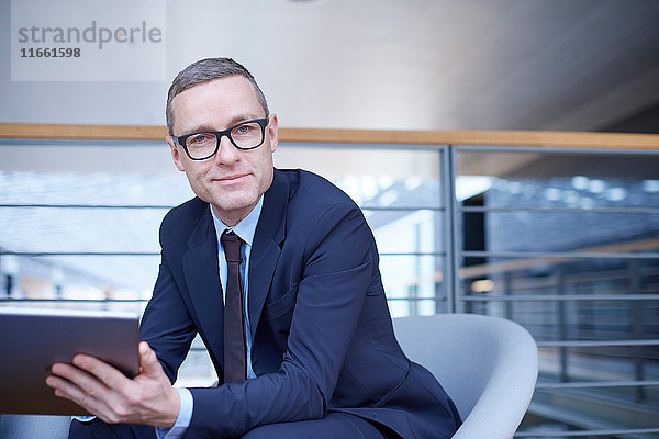 Porträt eines selbstbewussten Geschäftsmannes mit Laptop auf dem Bürobalkon
