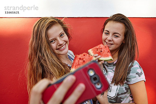 Mädchen im Teenageralter  die Selbsthilfe nehmen und Wassermelone essen