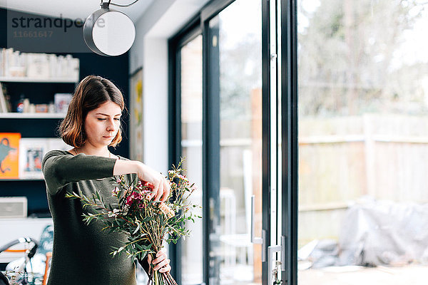 Floristenschüler arrangiert Blumenstrauß im Blumenarrangement-Workshop