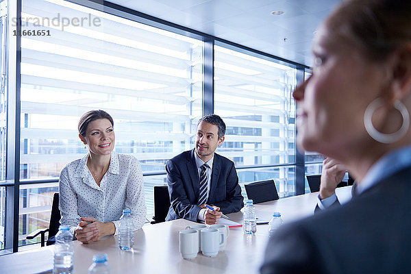 Blick über die Schulter von Geschäftsfrauen und -männern  die bei einer Bürobesprechung zuhören