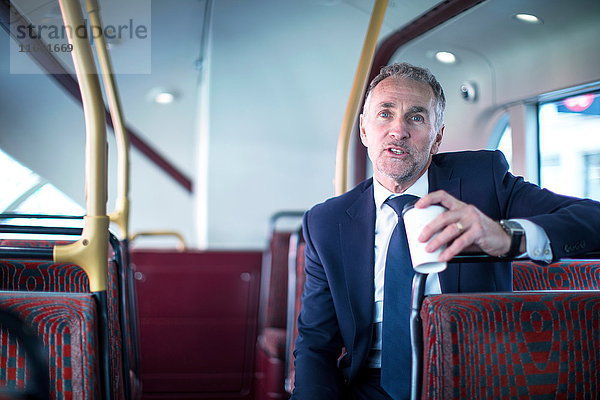 Geschäftsmann mit Kaffee zum Mitnehmen im Doppeldeckerbus