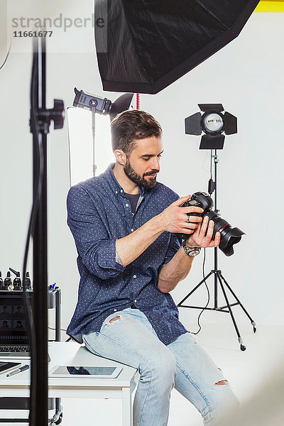 Männlicher Fotograf bespricht Fotoaufnahmen mit digitaler Spiegelreflexkamera im Fotostudio