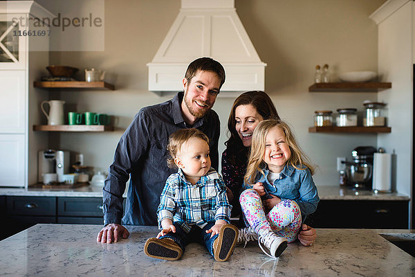 Porträt mittelgroßer Eltern mit Mädchen und Junge auf der Küchentheke