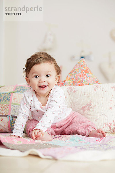 Porträt eines kleinen Mädchens  das auf einer Decke sitzt und lacht
