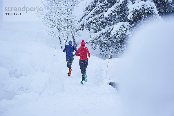 Rückansicht von Läuferinnen und Läufern  die im Tiefschnee auf der Bahn laufen  Gstaad  Schweiz