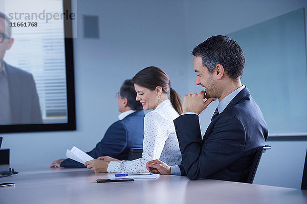 Geschäftsfrau und Mann grinsen während einer Büro-Telefonkonferenz