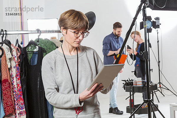 Stylist beim Betrachten eines digitalen Tabletts im Fotostudio