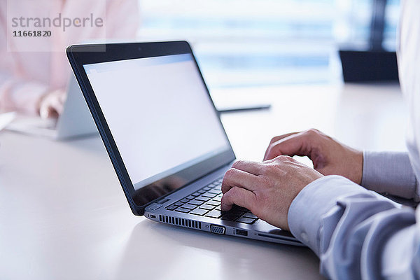 Hände eines Geschäftsmannes beim Tippen am Laptop am Büroschreibtisch