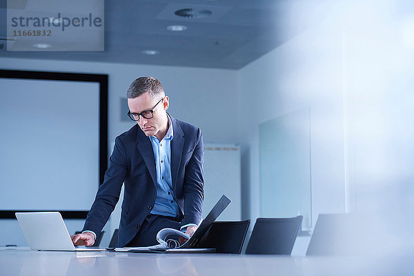 Geschäftsmann tippt am Laptop am Tisch im Sitzungssaal