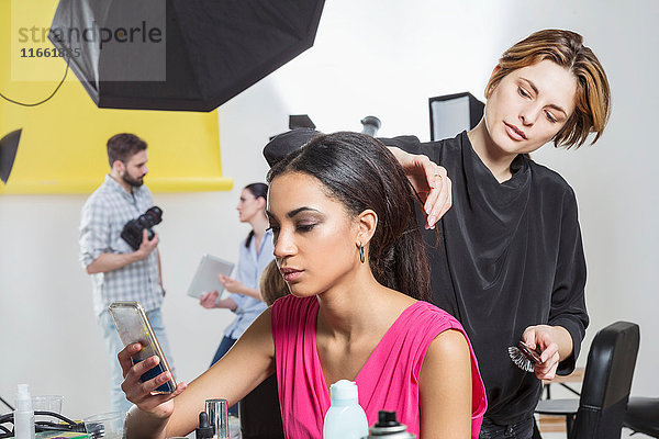 Friseur frisiert langes Haar eines Modells im Fotostudio