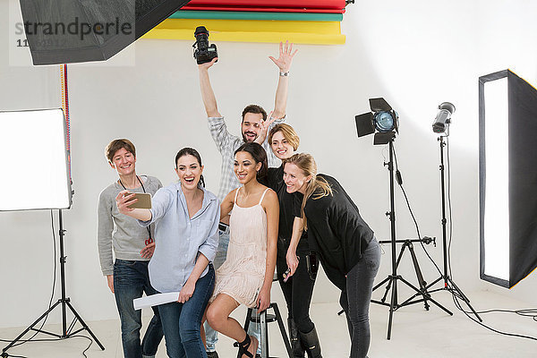 Stylisten  Modell und Fotograf beim Smartphone-Selfie im Fotostudio