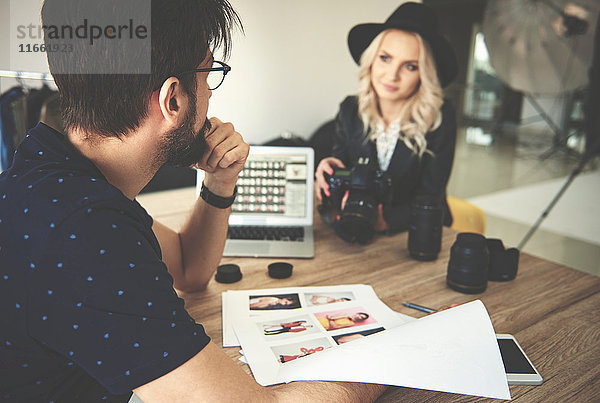 Fotograf und Stylist beim Betrachten von Fotos im Fotostudio