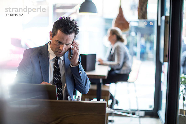 Reife Geschäftsleute  die im Restaurant telefonieren