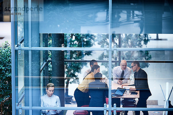 Fensteransicht von Geschäftsfrauen und -männern  die im Konferenzraum diskutieren