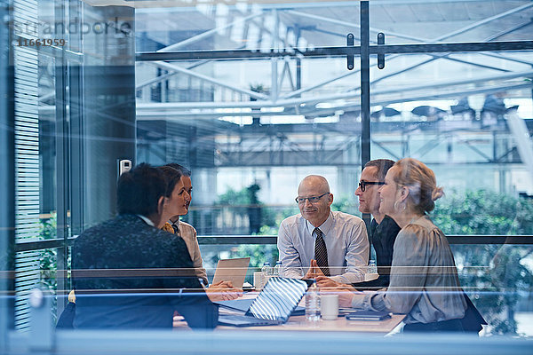 Fensteransicht von Geschäftsfrauen und -männern  die im Konferenzraum diskutieren