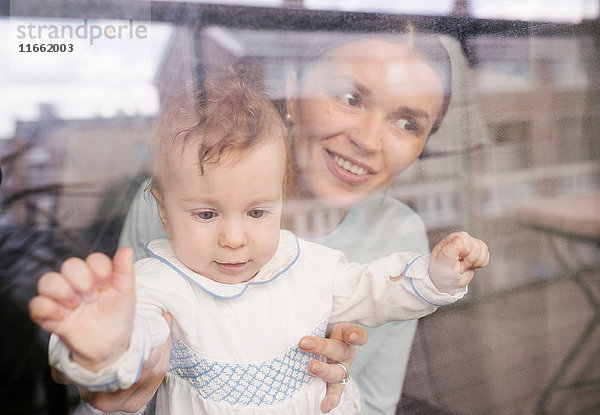 Mutter und Baby schauen durch ein Glasfenster
