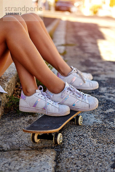 Zwei Freundinnen  Entspannung im Freien  Füße auf Skateboard ausruhen  niedriger Abschnitt