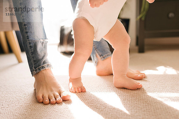 Barfüsse von Mutter und Kind auf Teppich im Wohnzimmer