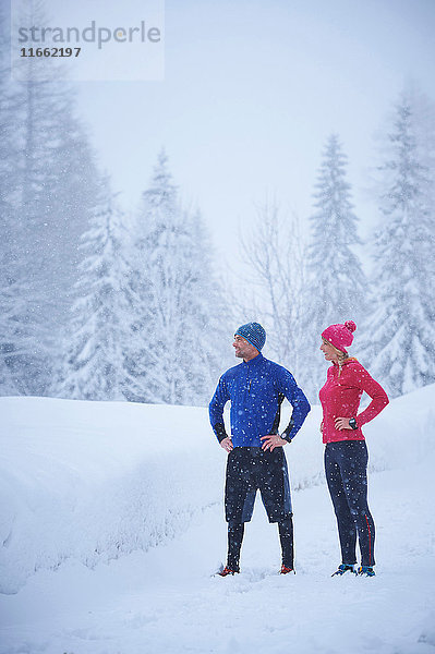 Läuferinnen und Läufer beobachten Schneefall von einer tief verschneiten Loipe  Gstaad  Schweiz