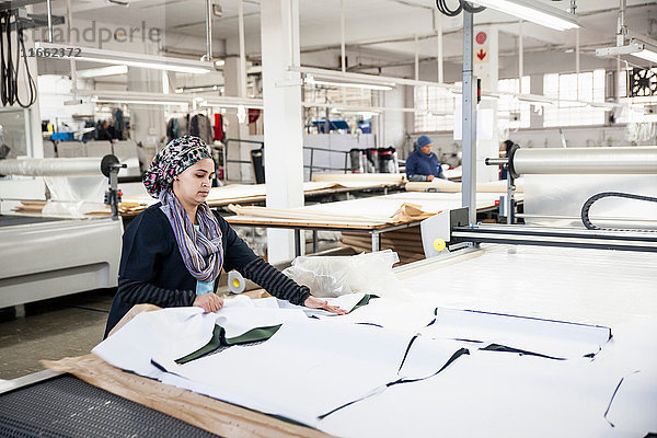 Fabrikarbeiter entfernt geschnittene Textilmuster von einer Musterschneidemaschine in einer Bekleidungsfabrik