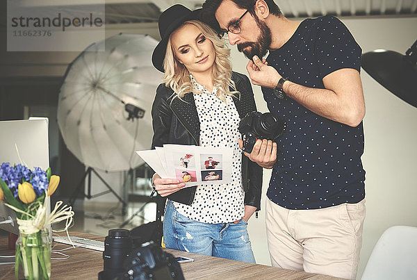 Fotograf und Stylist beim Betrachten von Fotos im Fotostudio