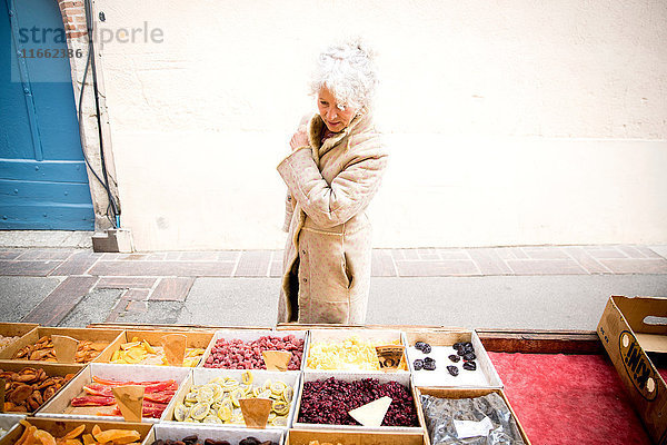 Ältere Käuferin betrachtet getrocknete Lebensmittel auf dem lokalen französischen Markt